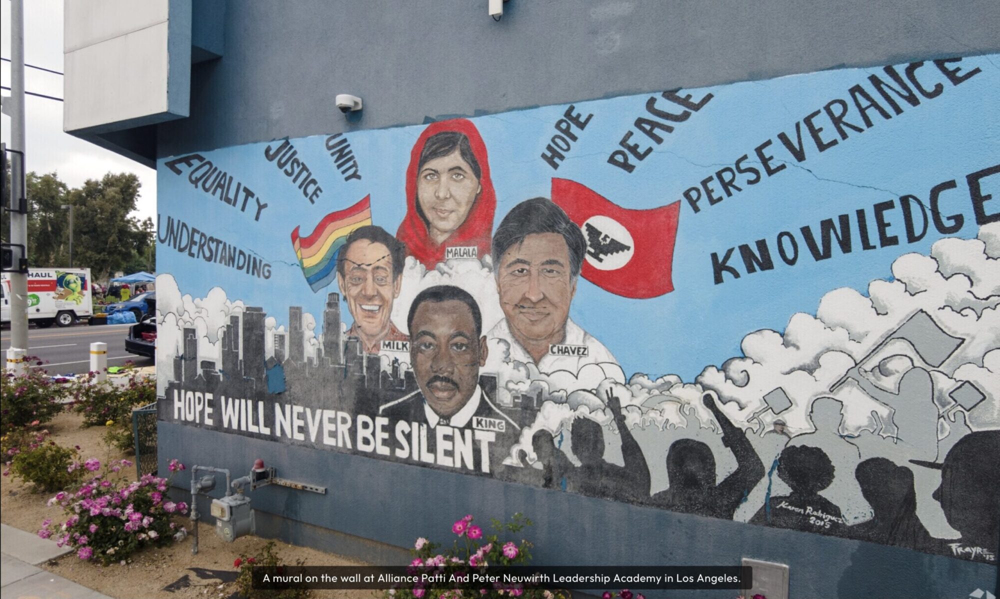 A mural featuring portraits of Malala Yousafzai, Cesar Chavez, Martin Luther King Jr., and others with words like "hope," "peace," and "equality" painted on a building wall.